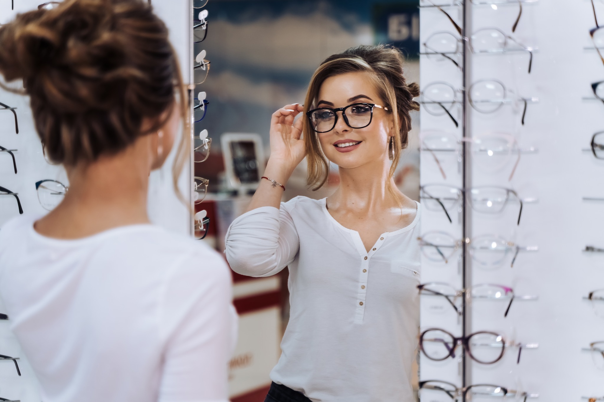 Young woman smiling and putting on glasses.