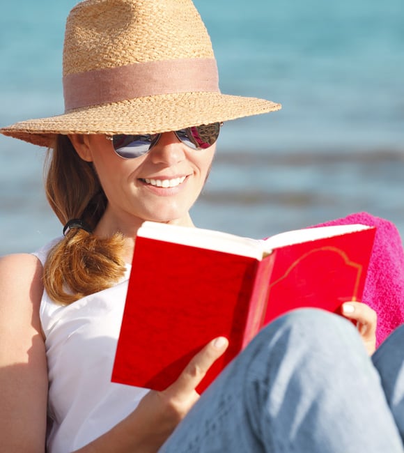 Woman on the beach reading while wearing bifocal sunglasses