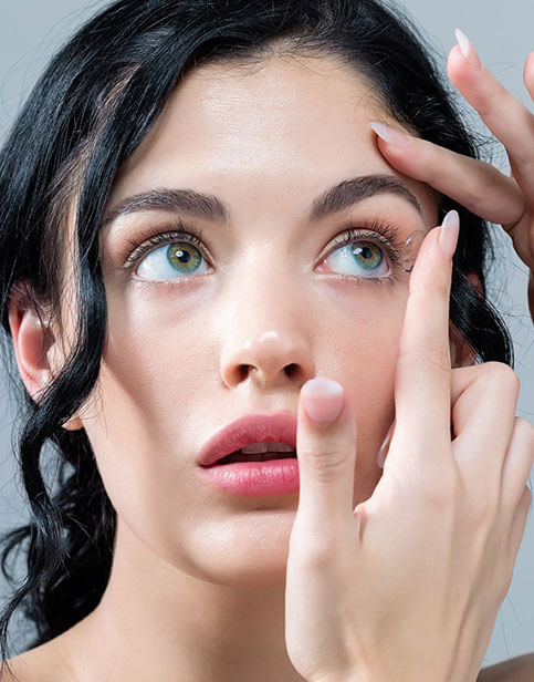 Woman putting on soft contact lenses